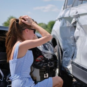 Worried driver standing beside a damaged car after an accident with an uninsured driver